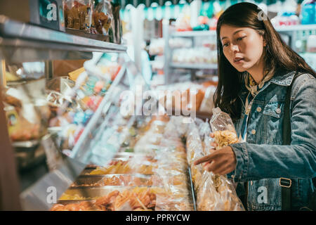 Femme client parle au vendeur dans le magasin ce qu'elle veut acheter. Elle tient un sac de fruits secs. Banque D'Images