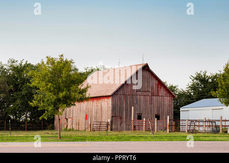 Ancienne grange en bois rouge pâle à côté d'une route dans la campagne en dehors de Wichita, Kansas, USA. Banque D'Images