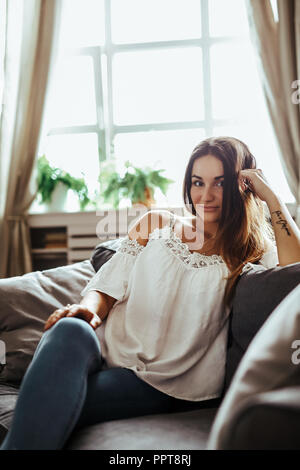 Belle et heureuse femme est assise sur le canapé Banque D'Images