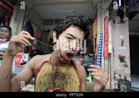 Jeune homme avec grand éclat de verre dans la bouche et les joues de piercing à Phuket, Thaïlande Festival Végétarien Banque D'Images