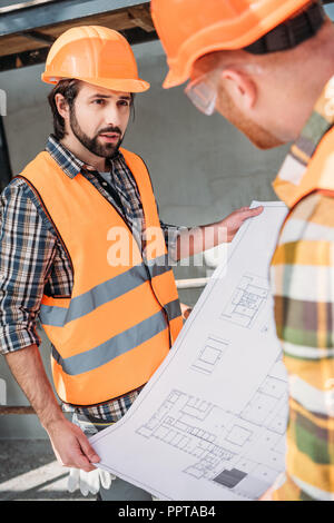 Les constructeurs avec le plan directeur ayant conversation at construction site Banque D'Images