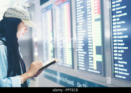 Beau billet woman using smartphone à l'aéroport. Jeune asiatique le meilleur contrôle de l'heure d'embarquement avec un téléphone mobile app dans le terminal ou la gare. À Banque D'Images