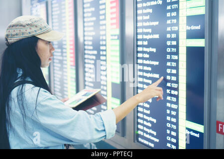 Beau billet woman using smartphone à l'aéroport. Jeune asiatique le meilleur contrôle de l'heure d'embarquement avec un téléphone mobile app dans le terminal ou la gare. À Banque D'Images