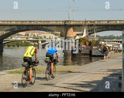 Deux personnes à vélo sur un chemin le long de la rivière Vltava dans le centre de Prague Banque D'Images