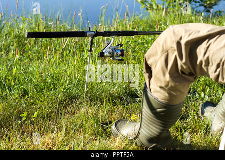 Angler's leg dans Wellington contre la prairie et l'eau. Piquet de terre monté sur un rack Banque D'Images