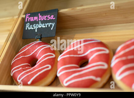 Une vue en gros plan d'une sélection de framboise fruitée donuts en vente dans une boulangerie Banque D'Images