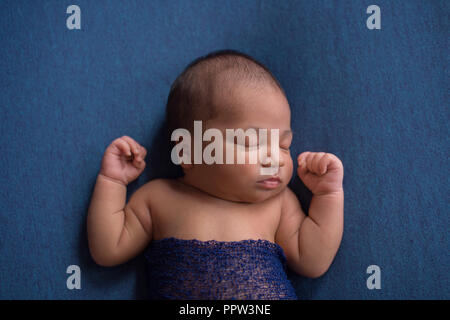 Portrait d'un coin couchage, d'un jour neuf nouveau-né garçon. Tourné dans le studio sur le denim blue matériau. Banque D'Images