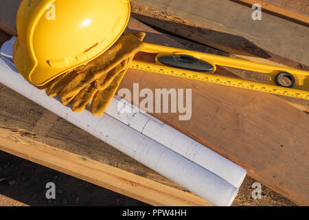 La construction du résumé d'un casque, des gants, de niveau et de plans de maison reposant sur plancher bois. Banque D'Images