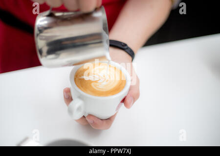 Barista verse une tasse de café latte et crée une belle image Banque D'Images