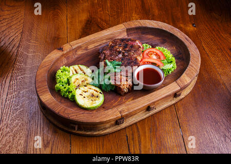 Sex steak avec tomates, salade, courgette, verts et de la sauce sur une planche de bois. Des en-cas pour la bière au restaurant Banque D'Images