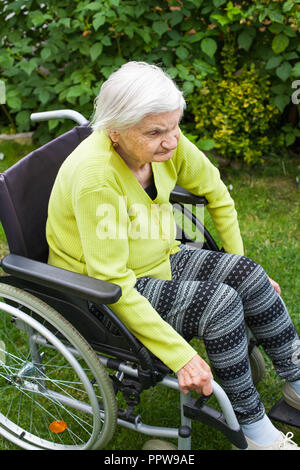 Vieille dame assise en fauteuil roulant souffrant de démence en plein air temps de dépenses Banque D'Images