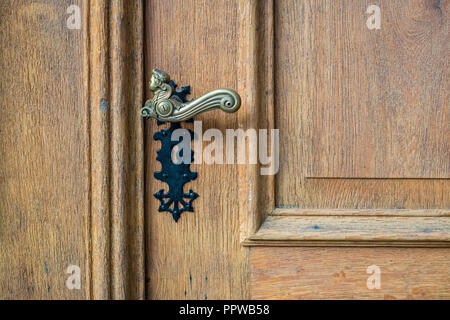 Regarder une poignée de porte de fer noir d'une porte de bois d'un bâtiment dans la ville de Thun dans les Alpes bernoises en Suisse. C'est une belle porte d'époque Banque D'Images