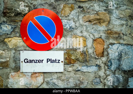 Contre un mur de brique dans la ville suisse de Lucerne un panneau bleu et rouge indique qu'il est interdit de stationner sur cette place. Banque D'Images