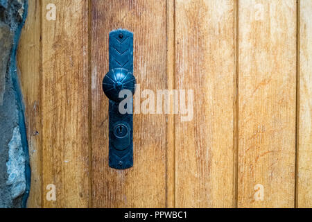 Regarder une poignée de porte de fer noir d'une porte de bois d'un bâtiment dans la ville de Thun dans les Alpes bernoises en Suisse. C'est une belle porte d'époque Banque D'Images