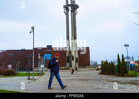 Gdansk, occidentale, Pologne : un homme marche à travers la place de la solidarité. En arrière-plan, le Centre de la solidarité européenne (ouvert en 2014) à côté de l'entrée de Banque D'Images