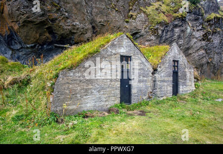 Deux vieilles maisons aux toits de gazon près d'un rocher en Islande. Banque D'Images