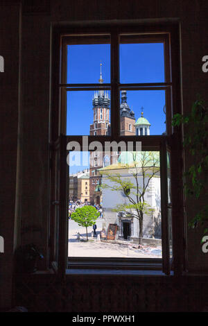 Cracovie, Pologne : la Basilique Sainte-Marie et Saint Adalbert l'église à la place du marché comme vu encadré par une fenêtre de l'hôtel. Banque D'Images