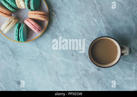 Les feuilles, une tasse de café et gâteaux macarons français pastel sur une surface en marbre. Mise à plat de la composition ci-dessus, vue de dessus . Contexte with copy space Banque D'Images