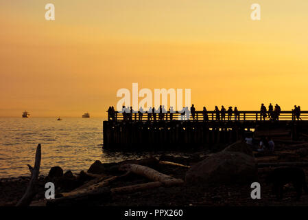 Silhouettes de personnes sur le quai au coucher du soleil à Ambleside, à West Vancouver, BC, Canada. Banque D'Images