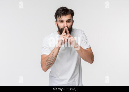 Secret, gossip concept. Jeune homme whispering a secret derrière sa main. Businessman isolated on white background studio. Jeune homme émotif. Les émotions humaines, l'expression faciale concept. Banque D'Images