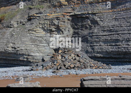 Un grand éboulement montrant le trou qu'il a laissé dans la falaise et l'énorme tas de débris sur la côte située la marée va progressivement se disperser. Banque D'Images