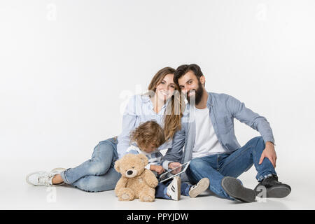 Smiling family sitting together at studio blanc et regarder leurs dessins animés préférés sur ordinateur portable. Banque D'Images