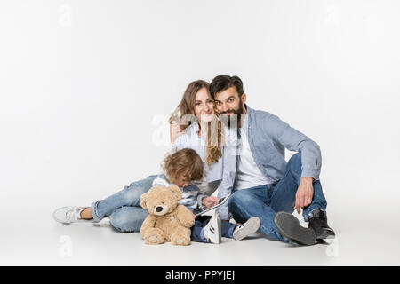 Smiling family sitting together at studio blanc et regarder leurs dessins animés préférés sur ordinateur portable. Banque D'Images