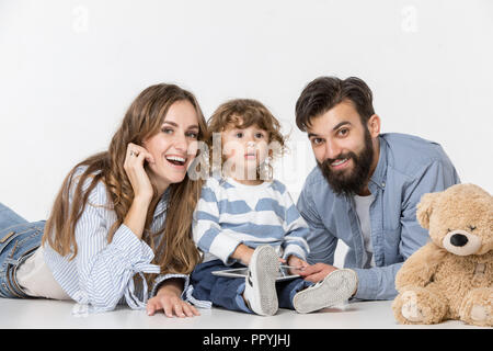 Smiling family sitting together at studio blanc et regarder leurs dessins animés préférés sur ordinateur portable. Banque D'Images