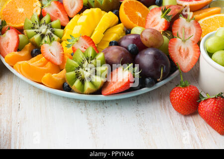 Variété de fruits et de baies, fraises, bleuets plateau orange mangue, pomme, raisins, kiwis sur le bois blanc, l'arrière-plan copie espace pour t Banque D'Images