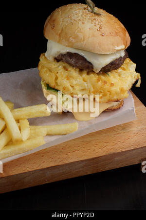 Sandwich omelette avec l'oeuf, le fromage et les hacher avec les frites sur un conseil. Banque D'Images