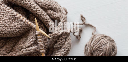 Beige laine à tricoter et des aiguilles à tricoter on white background. Le tricotage d'un passe-temps. Accessoires pour le tricot. Banque D'Images