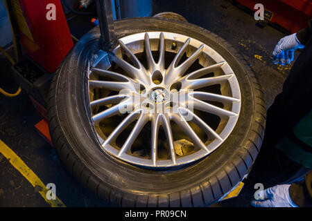 Ajusteur mécanicien pneu / montage / montage d'un pneu neuf ( faites par Goodyear ) sur une voiture / Voitures / roue jantes en alliage jante à l'aide d'une machine. UK. (102) Banque D'Images