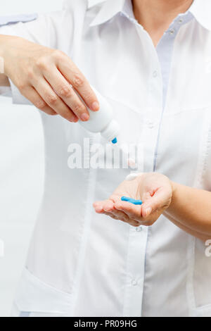 Female doctor holding un pot et l'offre de pilules. Les comprimés hors de la bouteille. Selective focus on pills Banque D'Images