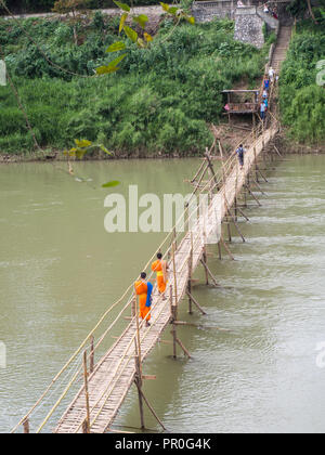 Les moines bouddhistes vêtus de orange traversant un pont de bambou, Luang Prabang, Laos, Indochine, Asie du Sud, Asie Banque D'Images