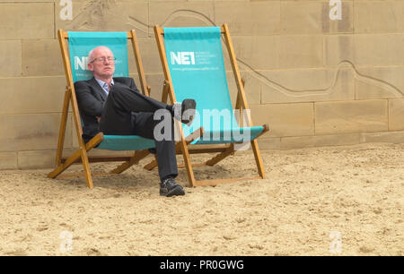 Businessman wearing a suit endormi dans une chaise longue sur la plage par l'homme sur les rives de la rivière Tyne Newcastle Banque D'Images