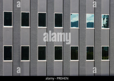 Détail d'un bâtiment gris gris - verre et briques. Deux étages. Réflexions du ciel dans les fenêtres Banque D'Images
