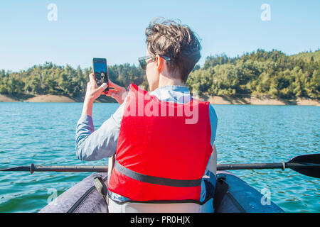 Jeune femme en tenant avec selfies smart phone tout en kayak sur le lac Lokvarsko à Gorski Kotar, Croatie. Sur l'expérience d'aventure Girl enjoying Banque D'Images