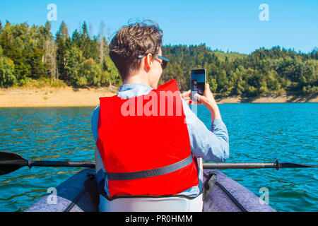 Jeune femme en tenant avec selfies smart phone tout en kayak sur le lac Lokvarsko à Gorski Kotar, Croatie. Sur l'expérience d'aventure Girl enjoying Banque D'Images