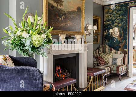 19e siècle tapisserie de verdure et Panneaux capitonnés banquette avec Andrew Martin stripe avec feu allumé Banque D'Images