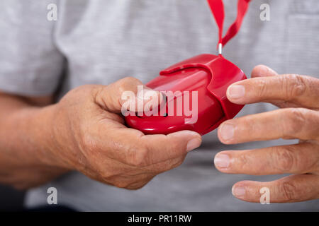 Close-up of a Senior Man's Hand Holding Red alarme personnelle Banque D'Images