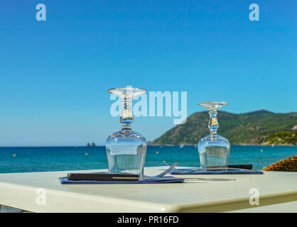 Un café élégant avec vue sur la mer sur la côte d'Azur vous attendent pour le déjeuner, servi avec des verres de table, vaisselle et serviettes Banque D'Images