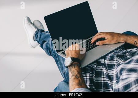 Portrait de tattooed man typing on laptop avec écran vide Banque D'Images