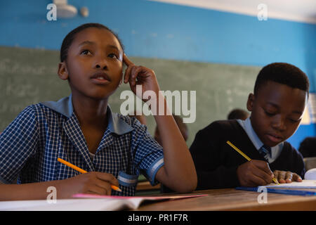 Schoolkids croquis holding pens in classroom Banque D'Images