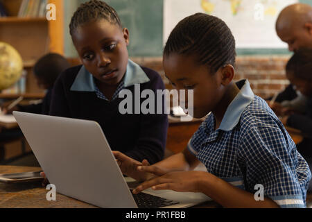 Schoolkids using laptop in classroom Banque D'Images