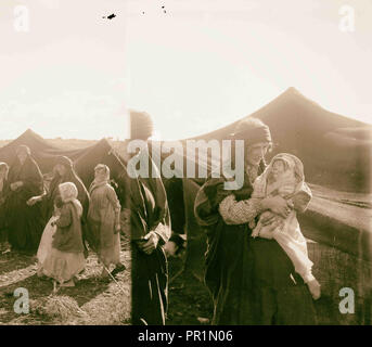 Types de Transjordanie. Mère et bébé emmailloté bédouins ; [les bédouines et les enfants en face de tente ; moulin en arrière-plan Banque D'Images