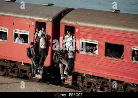 Sortir les passagers de trains de banlieue bondés sur les portes à la gare Bambalapitiya, Colombo, Sri Lanka Banque D'Images