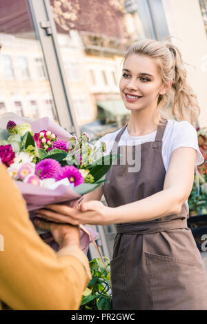 Smiling attractive donnant fleuriste beau bouquet de chrysanthèmes à client près de flower shop Banque D'Images