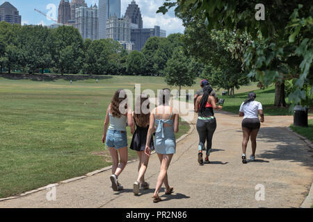 Des marcheurs et coureurs sur un chemin à Piedmont Park à Atlanta, GA sur une chaude journée d'été avec des bâtiments dans la distance Banque D'Images