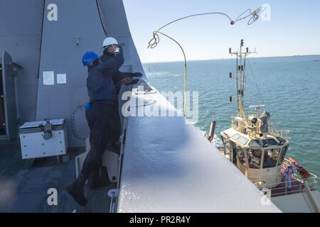 MORETON BAY (27 juillet 2017) Maître de Manœuvre Seaman Kelvin Wagner, de Houston, Texas, se soulève une ligne à un remorquage sur le gaillard de la transport amphibie USS dock Green Bay (LPD 20) tout en naviguant vers Brisbane, Australie. Green Bay, partie du Bonhomme Richard, groupe expéditionnaire fonctionne en Indo-Asia-région du Pacifique pour améliorer les partenariats et être une force de réaction pour prêt à tout type d'imprévus. Banque D'Images