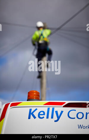 Telecome entrepreneurs Ingénieur de Kelly Communications escalade un poteau téléphonique pour fixer une ligne téléphonique sous-traitant travaillant pour BT Openreach en ma Banque D'Images